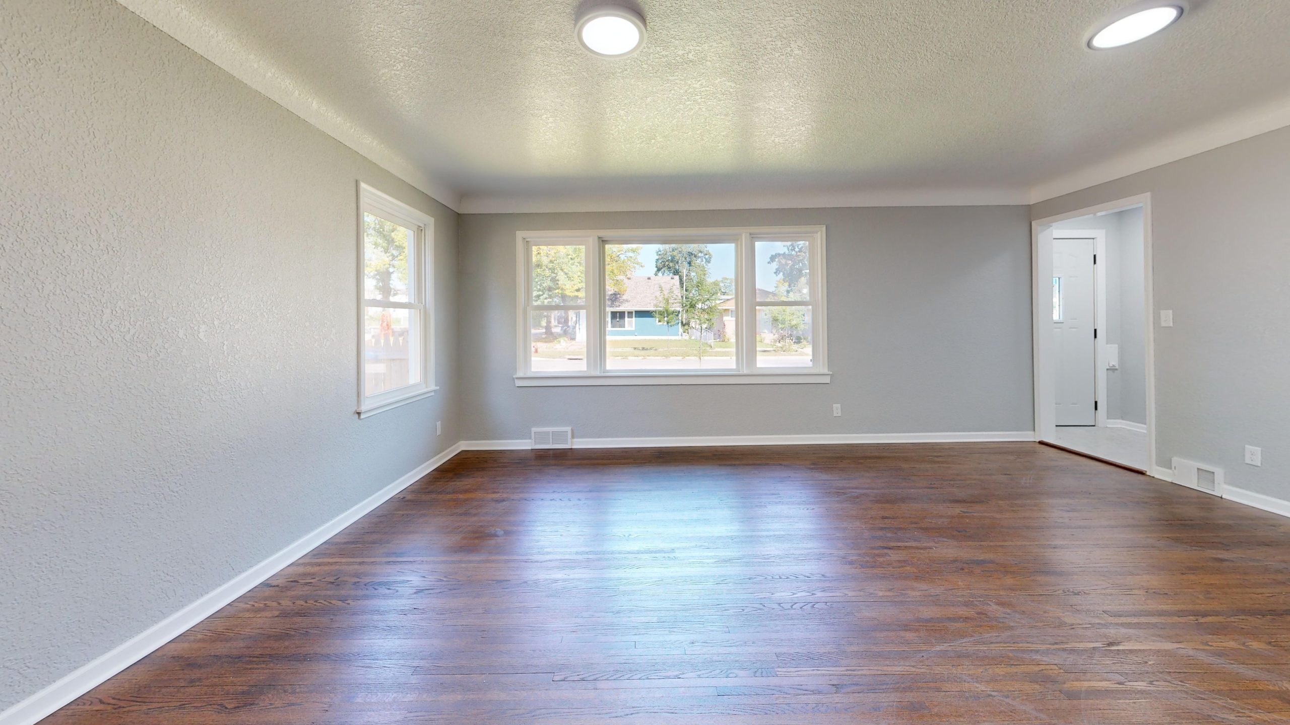 Dark hardwood flooring in an empty Alabama room with tall windows
