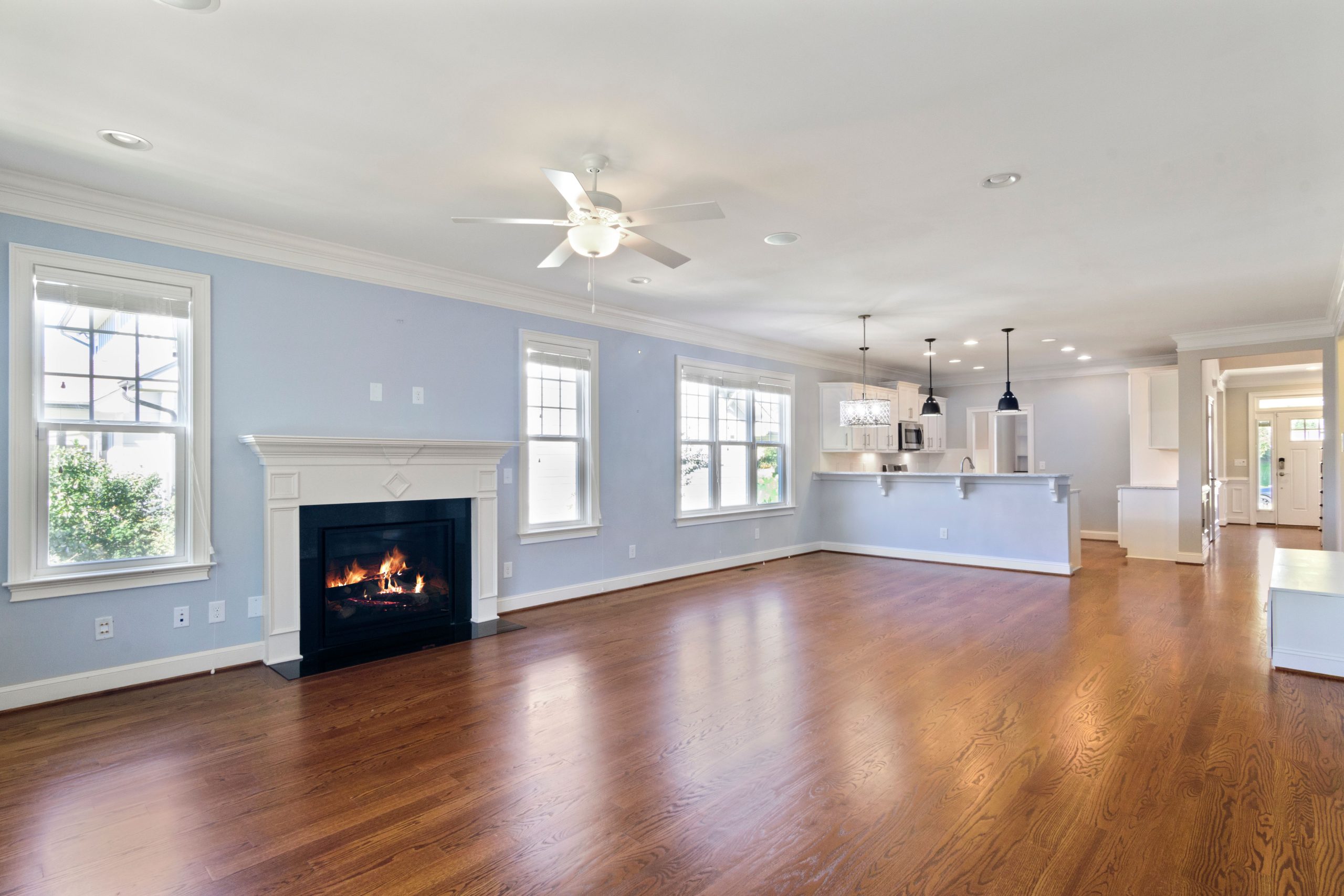 Warm oak hardwood flooring running through an empty open-plan Alabama living room with a lit fireplace