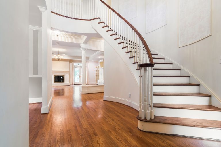 A curved wooden staircase with white balusters above an oak floor in an Alabama home