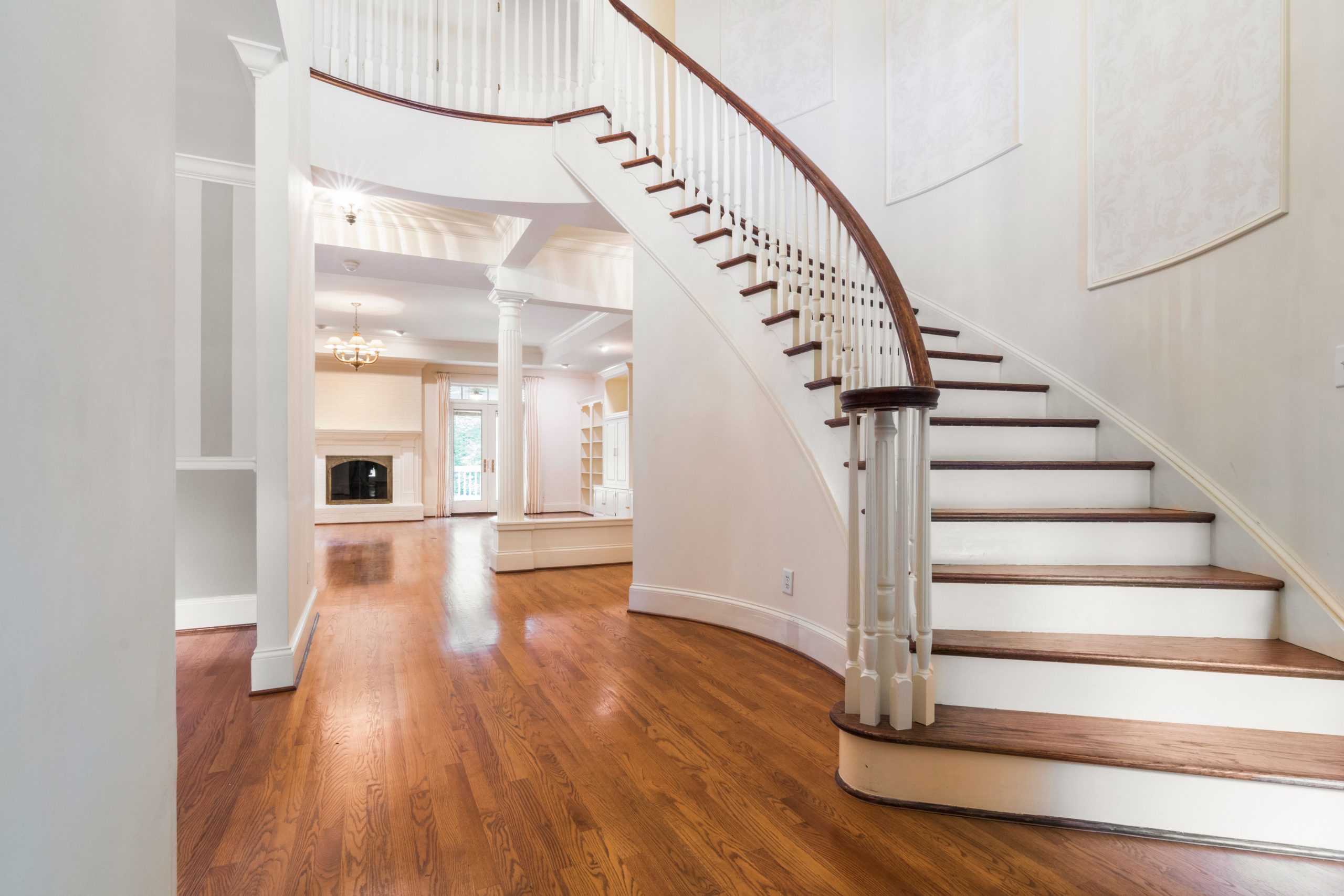 A curved wooden staircase with white balusters above an oak floor in an Alabama home