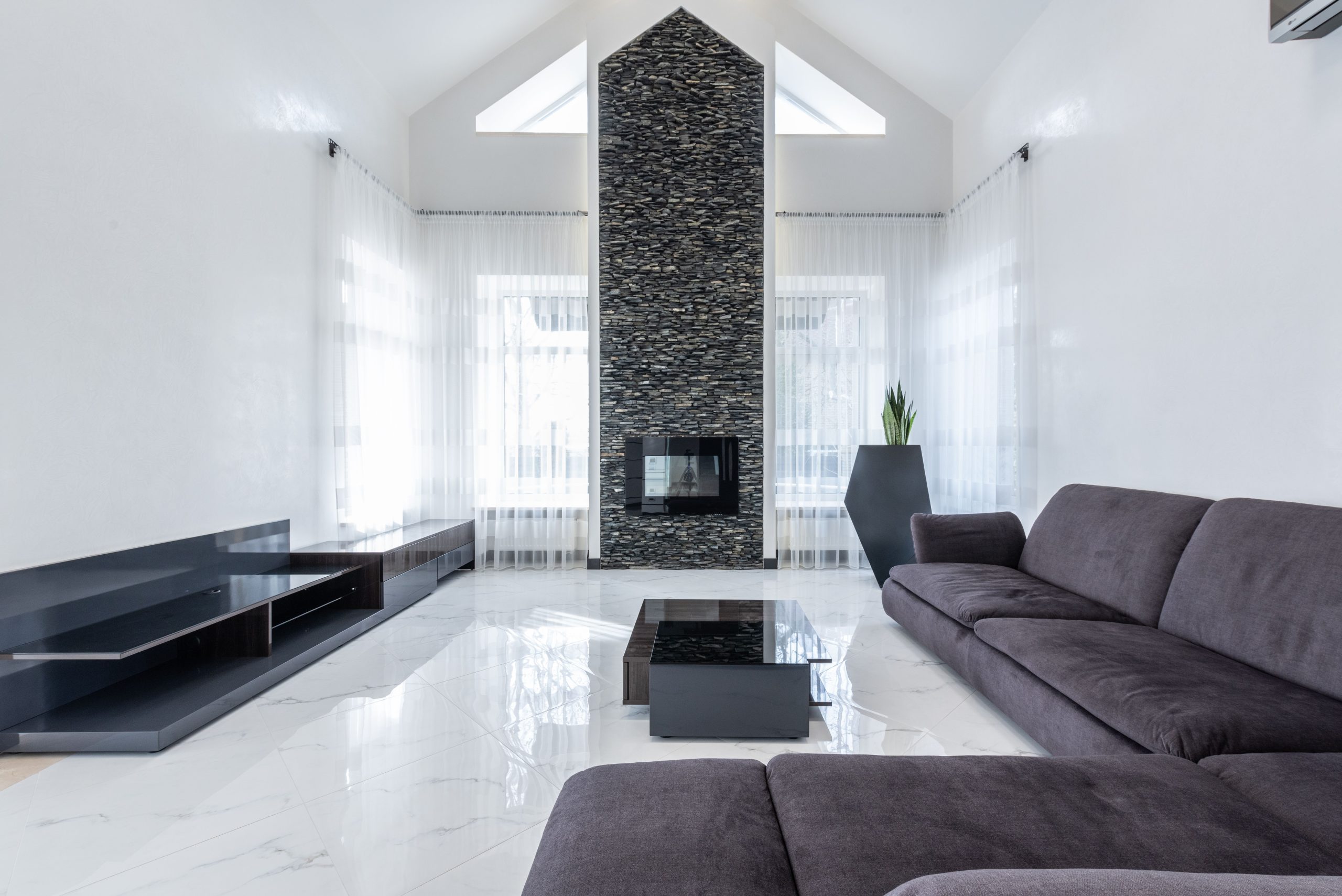 Polished marble-look stone flooring in a modern Alabama living room with a stacked-stone fireplace